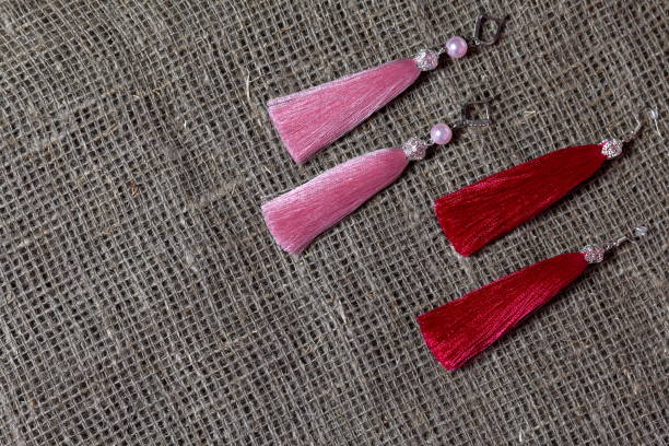 Earrings, tassels lie on a rough linen fabric. View from above.