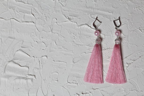 istock Earrings tassels. They lie on the surface covered with white decorative plaster. 1161646285