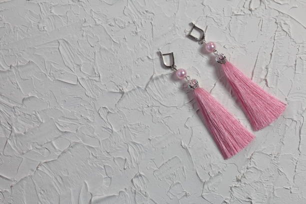 istock Earrings tassels. They lie on the surface covered with white decorative plaster. 1161646286