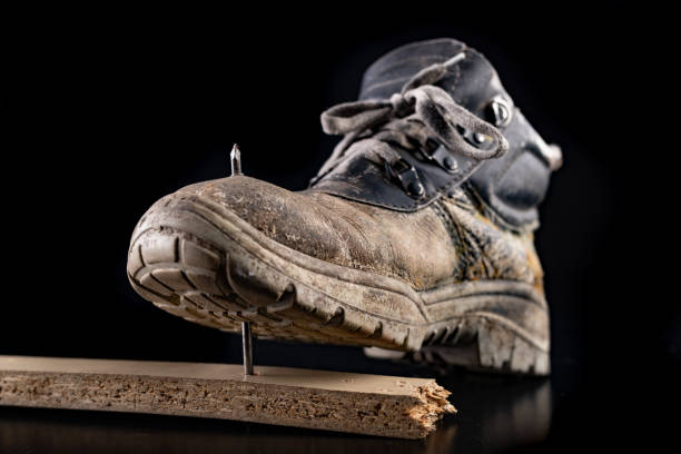 istock Work shoe pierced with a steel nail. Working clothes during a work accident. Dark background. 1161649188