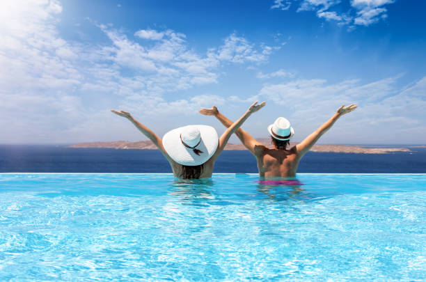 Traveler couple enjoys the view to the Mediterranean sea in a pool Happy traveler couple with sunhats in a infinity swimming pool enjoys the view to the Mediterranean sea horn of africa photos stock pictures, royalty-free photos & images