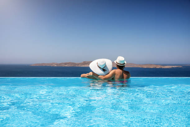 地中海を楽しむインフィニティプールでの旅行者カップル - sea swimming greece women ストックフォトと画像