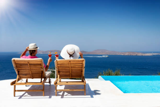 istock Couple sits on luxury sunbeds by the pool with aperitif drinks 1161649337