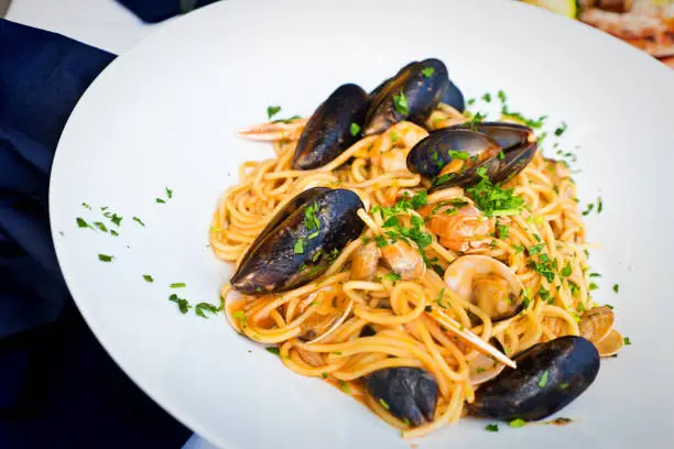 A traditional Italian cuisine. Pasta Spaghetti served with mixed seafood, mussels, clams, shrimps and fish, on a tomato sauce.