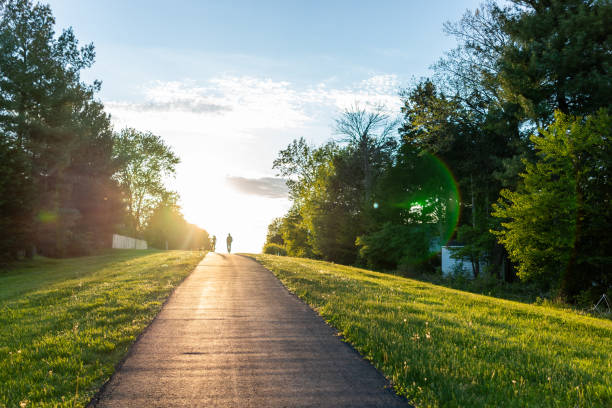 caminhada de sugarland run stream valley trail em herndon, virgínia, condado de fairfax na mola com estrada pavimentada do trajeto e silhueta do passeio dos pares - casal heterossexual - fotografias e filmes do acervo