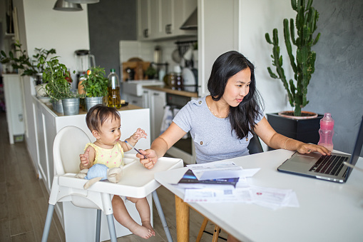 Young Asian mother working and spending time with baby at home