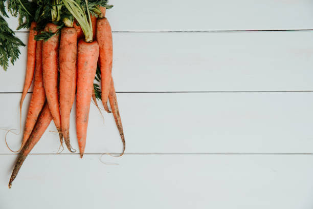 A bunch of carrots on a white wooden table.