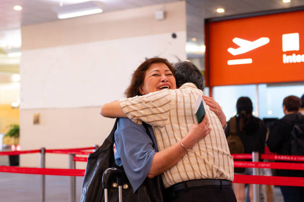 Smiling senior woman embracing man at airport Smiling senior woman embracing man at airport terminal. Loving male and female are greeting each other. They are going on vacation. airport hug stock pictures, royalty-free photos & images