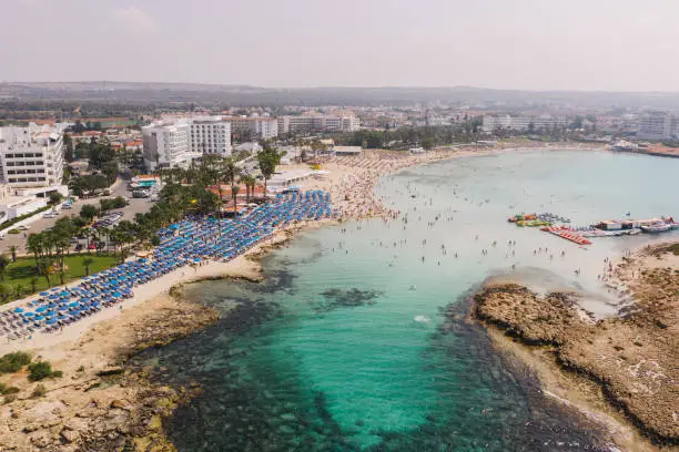 Scenic aerial view of crowded beach with blue umbrellas on Cyprus