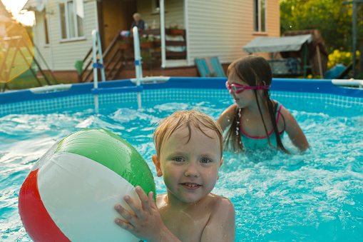 Children swimming in pool in summer evening
