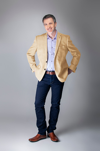 Middle-aged Caucasian businessman looking posh wearing modern fall collection style beige jacket.  Depicts confident and mature stylish fashion.  Shot in studio for catalog look.