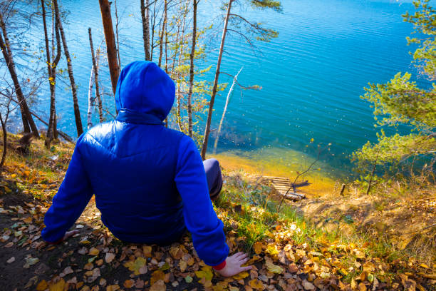 Teenager boy lonely contemplation summer countryside landscape on river bank during countryside summer holidays