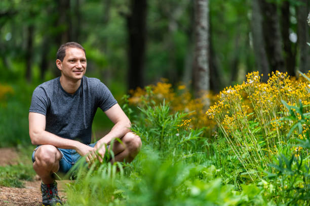 homme heureux dans l'histoire du sentier de nature de forêt dans les montagnes appalachiennes de crête bleue de crête bleue de shenandoah par des fleurs jaunes sur le chemin - appalachian trail dirt road footpath appalachian mountains photos et images de collection