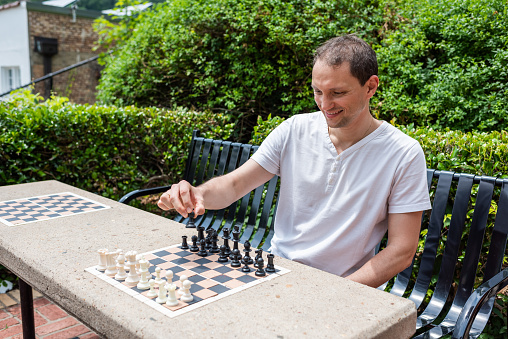 Chess table in park in Hot Springs, Arkansas with man playing during summer day sitting on bench