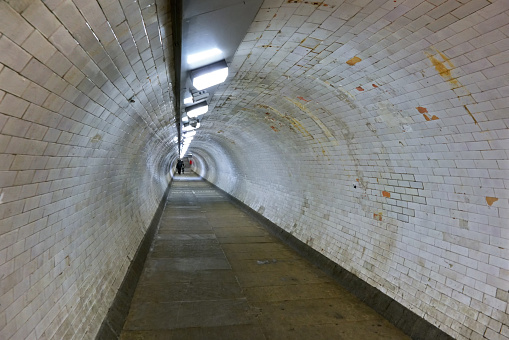 Wide angle photo of Greenwich foot tunnel under river Thames, people walking away in distance.