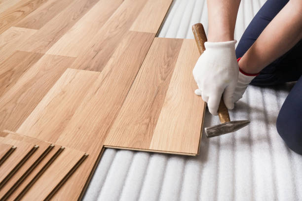 istock Installing laminated floor, detail on man hands fixing one tile with hammer, over white foam base layer 1161676110