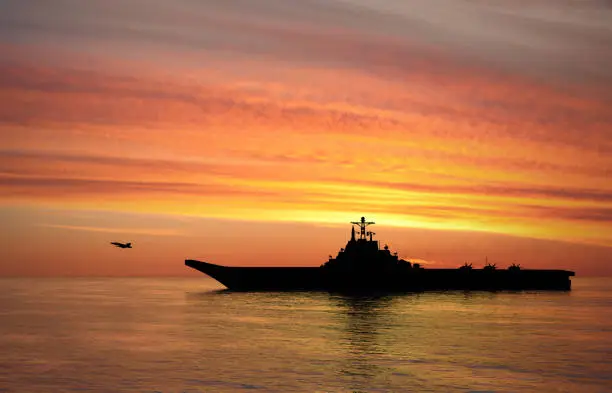 Aircraft carrier on sea at sunset
