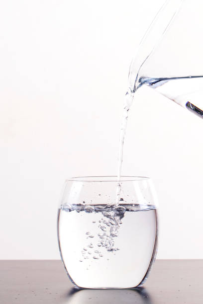 istock Pouring Water From Pitcher Into Glass, isolated on a white background with copy space 1161685371