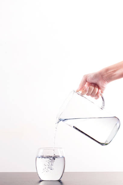 istock Pouring Water From Pitcher Into Glass, isolated on a white background with copy space 1161685375