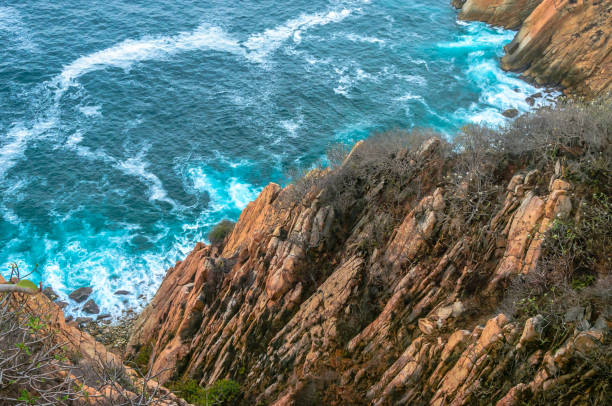 Blue sea with rocky shore in sunny afternoon, Acapulco, Mexico.