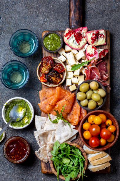istock Antipasto. Wine set appetizer. Ham serrano, smoked salmon, dried and fresh tomatoes olive cheese, wine on board. Top view, gray cncrete background 1161689708