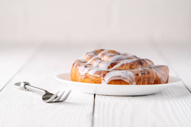 istock Large gourmet frosted cinnamon roll on white farmhouse table 1161702352