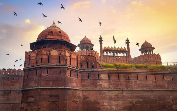 Historic Red Fort Delhi at sunrise with flying birds. Red Fort is a medieval Indian fort designated as a UNESCO World Heritage site stock photo