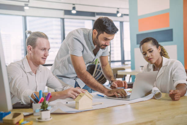 istock Young creative diverse group meeting and looking at project plan lay out on floor discuss or brainstorm business strategy with post note. Workshop for startup team in modern office. 1161704796