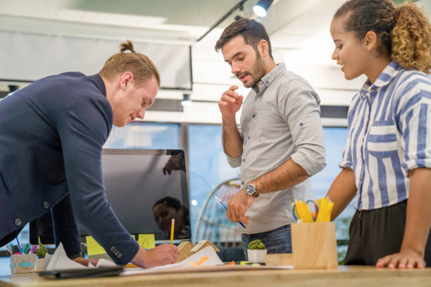 istock Young creative diverse group meeting and looking at project plan lay out on floor discuss or brainstorm business strategy with post note. Workshop for startup team in modern office. 1161704817