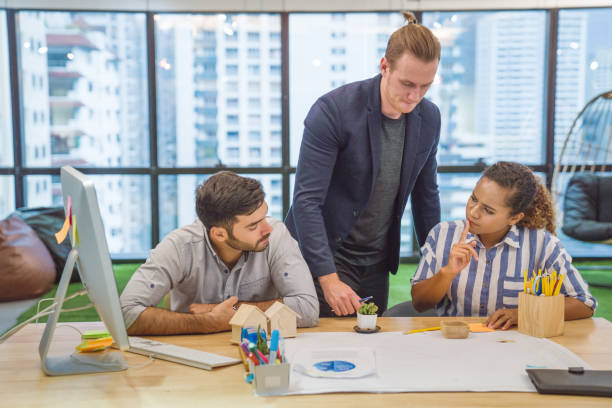 istock Young creative diverse group meeting and looking at project plan lay out on floor discuss or brainstorm business strategy with post note. Workshop for startup team in modern office. 1161704819