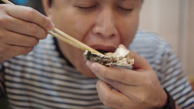 Asian Man eating Fresh Oyster for the first time.