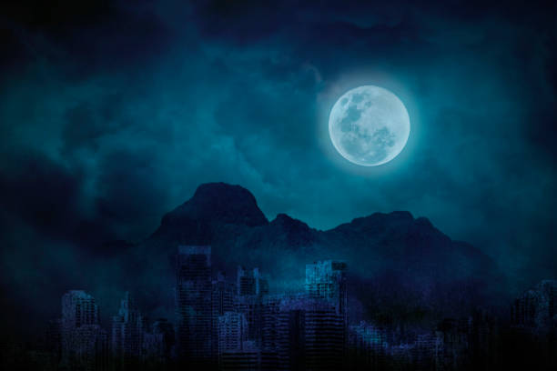 山と雲、真夜中に明るく暗い都市放棄の青い満月 ストックフォト