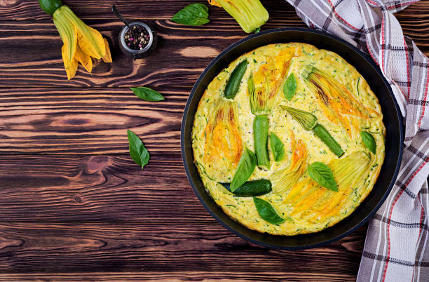 omelete cozido forno com abobrinha das flores na bandeja no fundo de madeira. vista superior com espaço da cópia. - squash flower - fotografias e filmes do acervo