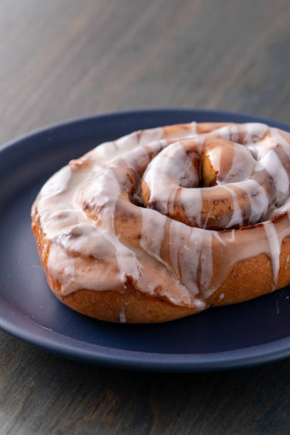 istock Large fresh frosted cinnamon roll on blue plate and table 1161713150