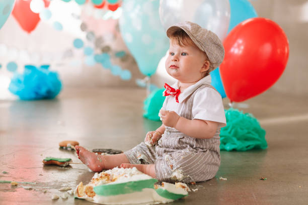 istock Baby boy touching his first birthday cake. Making messy cakesmash in decorated studio location. Dirty bare foot 1161713327