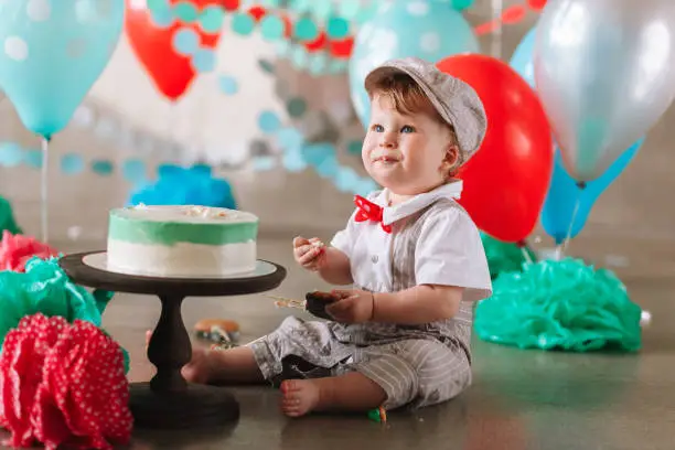 little baby boy eating cake on his first birthday cakesmash party.