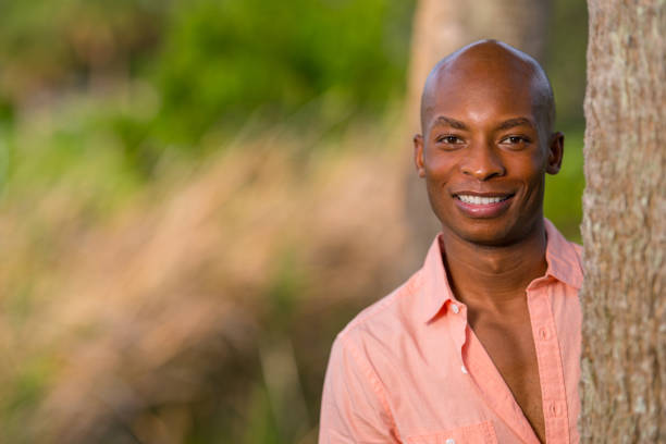 istock Handsome young African American man posing by a tree in the park 1161714098