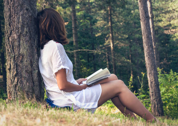 istock Beautiful woman reading book in forest. 1161716413