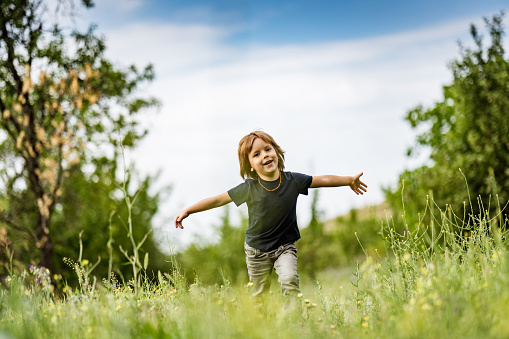Cute little boy running to camera outdoors