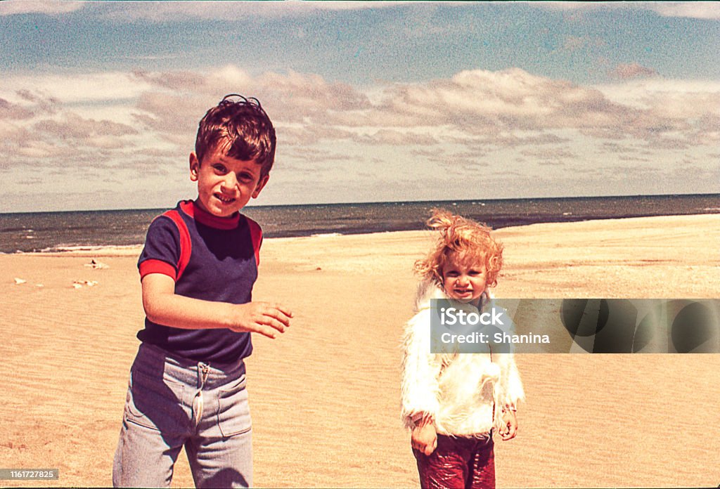 Cold day at the beach Vintage photo of a cute blonde little girl in with her brother at the beach on a cold day. Photography Stock Photo