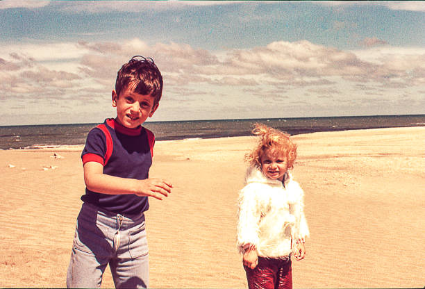 Cold day at the beach Vintage photo of a cute blonde little girl in with her brother at the beach on a cold day. vintage photos stock pictures, royalty-free photos & images