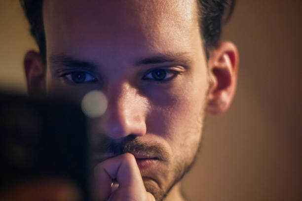 closeup of a caucasian man looking at mobile phone device screen. mobile phone addiction. - staring imagens e fotografias de stock