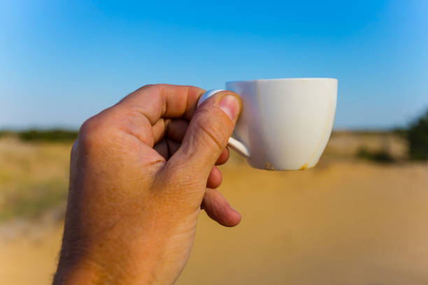 istock people hand take cofee cup on the sandy desert background 1161736437