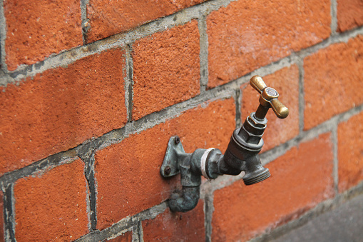 An Outdoor Wall Mounted Brass Water Tap.