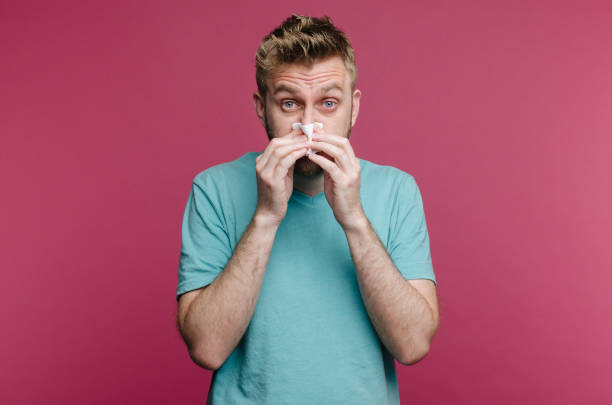 istock studio picture from a young man with handkerchief. Sick guy isolated has runny nose. man makes a cure for the common cold 1161742389