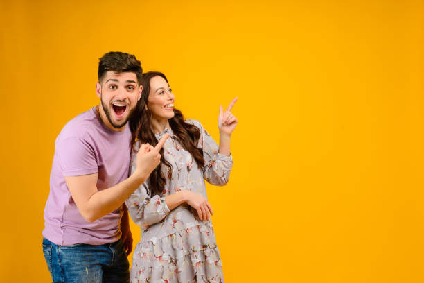 young man and woman isolated over bright yellow background - couple cheerful happiness men imagens e fotografias de stock