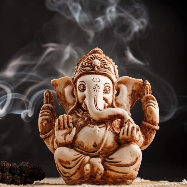 istock Hindu god Ganesh on a black background. Statue with incense smoke aromo sticks 1161753496