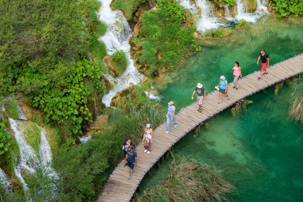 los excursionistas que pasan en cascadas de agua que corren hacia el lago kaluerovac de color azul en el parque nacional de los lagos de plitvice en croacia - europe high angle view waterfall water fotografías e imágenes de stock