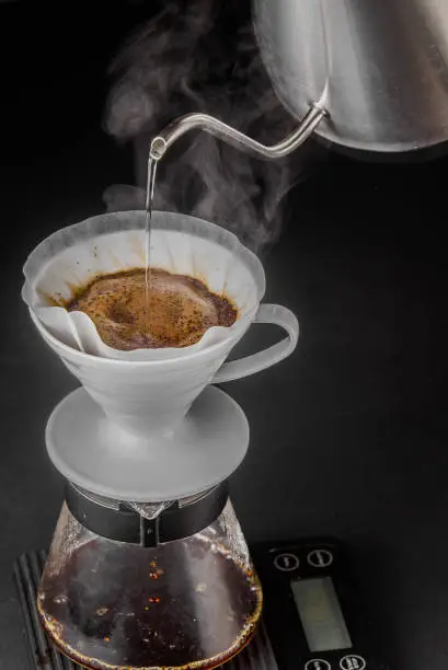 Alternative method of making coffee. coffeemaker is a manual pour-over style glass. Cofee brewing on black background