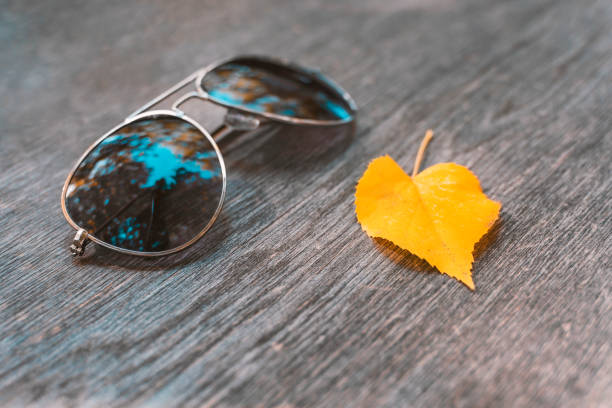 Autumn maple leaf and sunglasses on wooden table